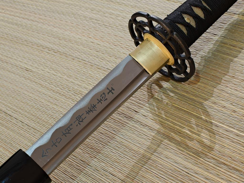 Katana resting on a tatami mat, blade engraved with kanji
